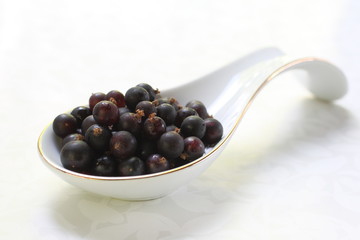 Black currant spoon on white. Berry black currant on a white background. 
