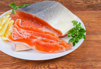 Partly sliced salted arctic char on dish on rustic table