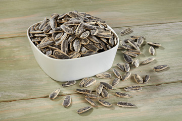 Sunflower seeds in white bowl on wooden background