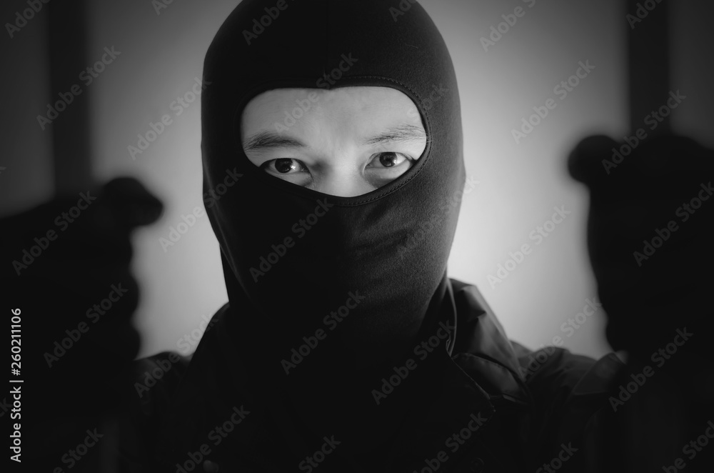 Wall mural Bandit wearing a mask is agitated prisoner in jail holding bars isolated on white background.