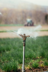 Irrigation plant system on a field, agriculture. Tractor in the blurry background.
