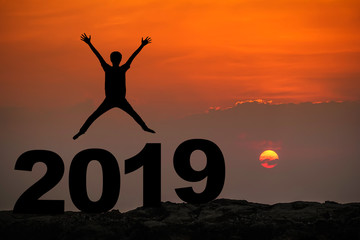 Silhouette of young man happy jumping and hand up between 2019 new year, sky and sun light background. copy space for text. Future and time passing concept.