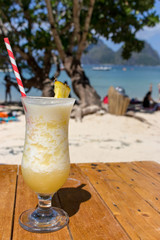 Fresh alcohol cocktail on the beach. Cold pina colada on seascape background. Cool pineapple cocktail with straw. Paradise background. Exotic resort. Tropical vacation and travel. Luxury relax.