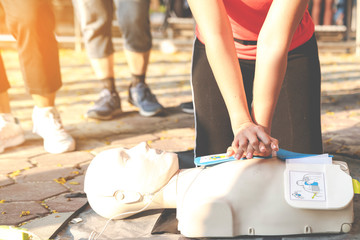 Asian female or runner woman training CPR demonstrating class in park by put hands and interlock...