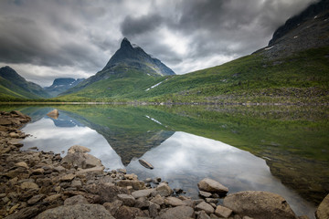 Dalatarnet mountain peak at Innerdalen with still lake and moody weather Norway