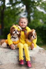 Girl with two dogs shih tzu. The girl in the yellow jacket. Dogs in yellow clothes. Girl walking with a dog.