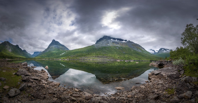Panorama of the innerdalen valley with the iconic Innerdalstarnet mountain rising from the clear lake in dark scenery Norway
