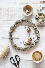 Making pussy willow wreath and decorating with quail eggs as a symbols of spring and Easter on a white wooden table