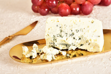 Fresh blue cheese on a golden saucer, honey and grapes.