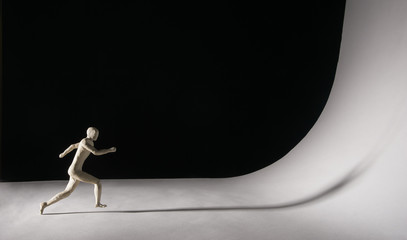 Man runs towards a big white wall. Difficult concept. Isolated on black background. With copy space...