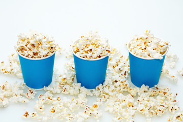 Three blue glasses with popcorn on a white background