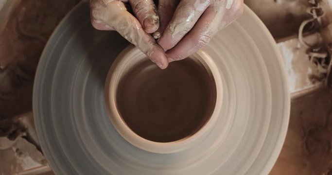 Potter making ceramic pot on the twisted pottery wheel. Top view. Potter at work, close up. Handmade, craft. White clay