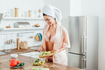 Sexy girl in lingerie and housecoat cooking salad in kitchen
