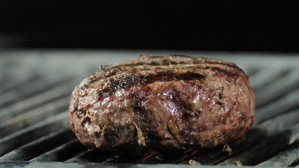 Close-up of a big juicy cutlet being grilled and taken with iron tongs