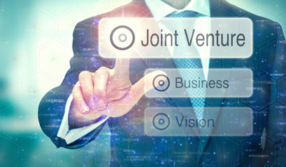 A business man selecting a button on a futuristic display with a Joint Venture concept written on...