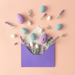 Creative layout made with spring flowers, leaves and Easter eggs on pastel pink background and...