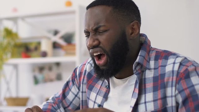 Afro-american man drinking hot beverage and feeling toothache, sensitive enamel