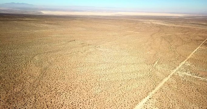 Aerial View: Angling Around Vast, Flat, Desert Landscape with Dirt Tracks in Joshua Tree, California