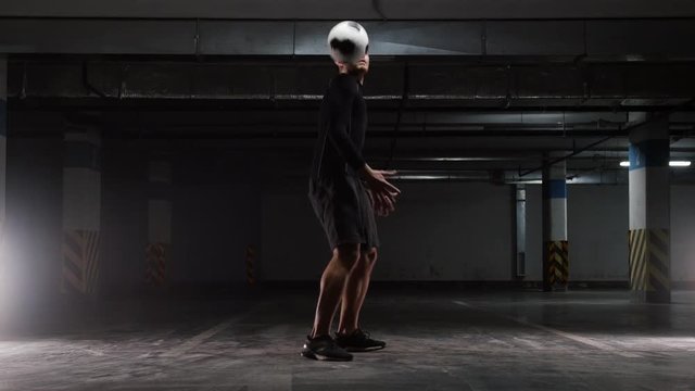 Underground parking. A young soccer man training tricks with the ball