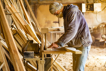 Carpenter works in the workshop of processing wooden boards, grinding machine, sander in the hands of a worker