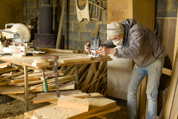 A man mills woodworker  in a woodworking workshop, a carpenter in a respirator with a milling...