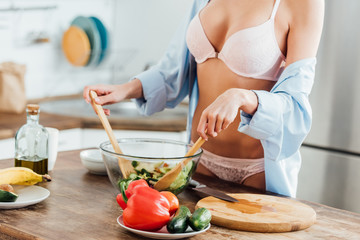 Cropped view of sexy girl in underwear and shirt cooking vegetable salad