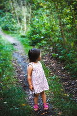 little girl stands on a path in the forest