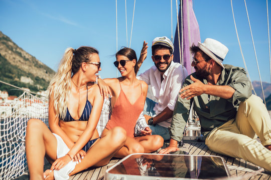 Smiling friends sitting on sailboat deck and having fun.Vacation, travel, sea, friendship and people concept