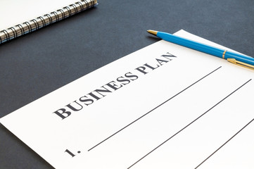 Strategy business plan with pen and notebook on dark table.
