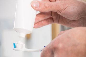 Person putting toothpaste on toothbrush