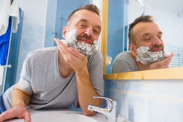 Guy shaving his beard in bathroom