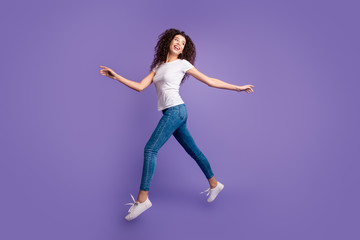 Fototapeta na wymiar Full length side profile body size photo funky beautiful she her lady jump high spread hands arms shopping store mall wear casual jeans denim white t-shirt sneakers isolated purple violet background