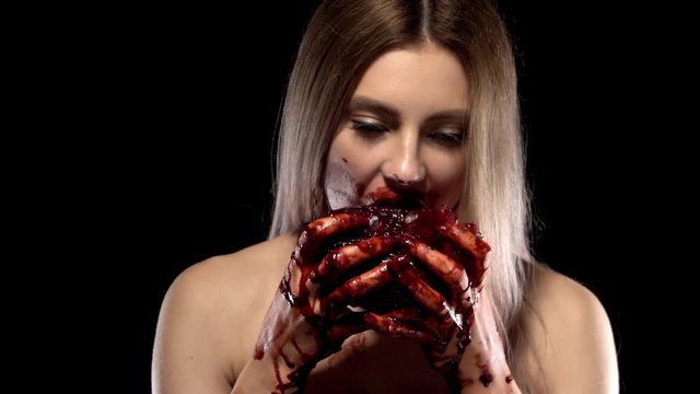 Creepy witch conducts a blood ritual, eagerly biting raw human heart, which she holds blood-stained hands