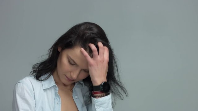 Brunette in studio portrait video shoot wwears jeans shirt with blowing hair slow motion from 60 fps Woman touches her hair and watching to the camera