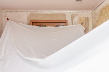 repairmen install stretch ceiling made of pvc vinyl film using a gas heat gun