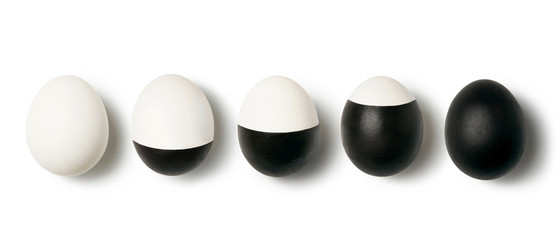 White and black colored eggs on a white background with copy space. Concept of changing life. Flat lay.