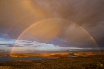 Obraz na płótnie Canvas Double rainbow during rain in the desert of Arizona against the background of clouds and a river.
