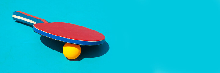 Red table tennis racket and ball on blue panoramic background whith copy space