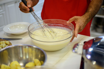 a man in the kitchen stirs a white dough in a bowl