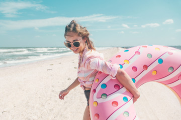 Girl relaxing on donut lilo on the beach - obrazy, fototapety, plakaty