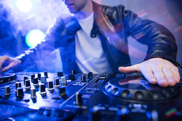 Dj mixing at party festival with red light and smoke in background - Summer nightlife view of disco club inside. Focus on hand