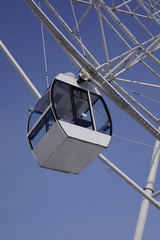 The cabin of the Ferris wheel against the blue sky.