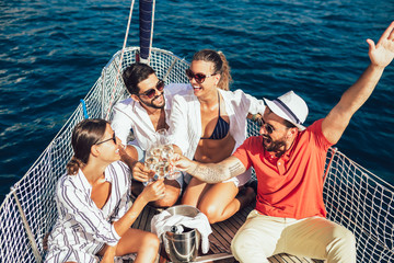 Smiling friends with glasses of champagne on yacht. Vacation, travel, sea, friendship and people concept