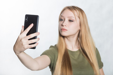 Beautiful young woman taking selfie on smartphone.