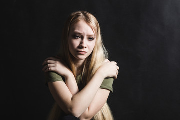 Fototapeta premium Sad young woman going to cry in a black background