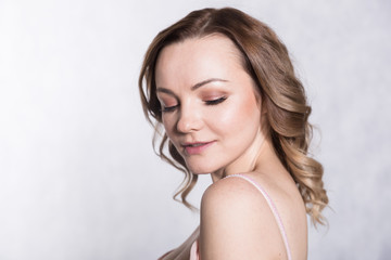 Portrait of beautiful young elegant female in pale pink wedding dress with big neckline, on a white background.