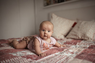 Cute cheeky toddler 5 months lying on bed