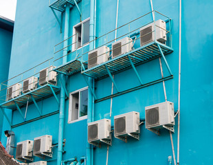 Air conditioner compressors on the turquoise wall outside