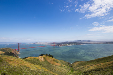 Fototapeta na wymiar Golden Gate Bridge shot from a high point. Strait of the Golden Gate. Sunny weather and green vegetation.