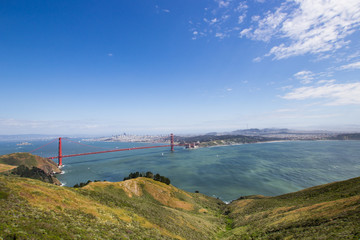 Golden Gate Bridge shot from a high point. Strait of the Golden Gate. Sunny weather and green vegetation.